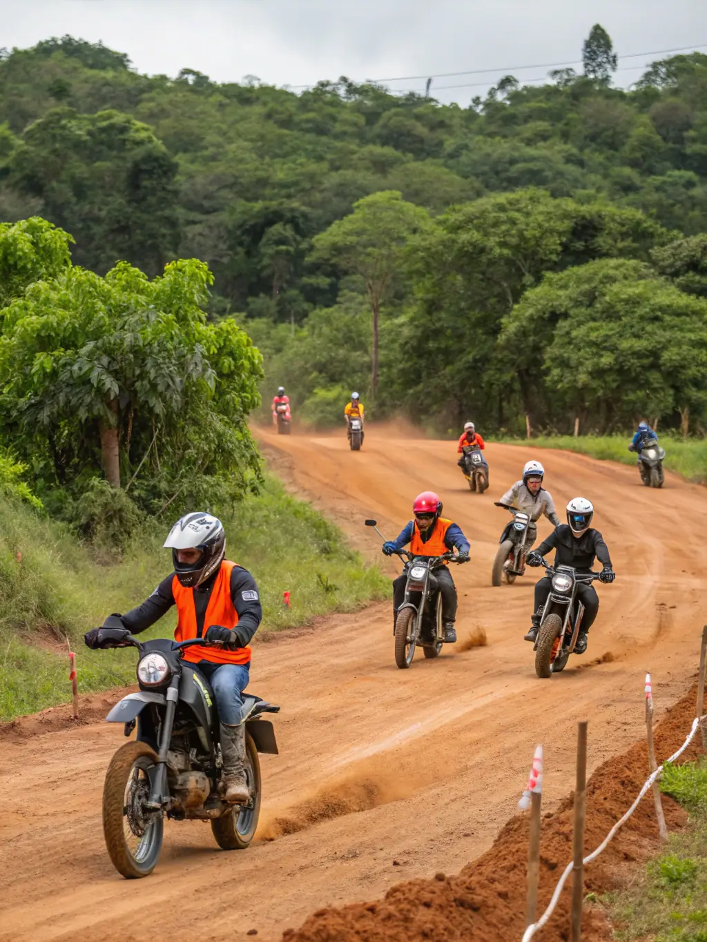 Teenagers, aged 13-16, are practicing advanced motorcycle riding techniques on a dirt track, under the guidance of experienced instructors, showcasing the advanced training program for older youth at Bourges Racing Team.